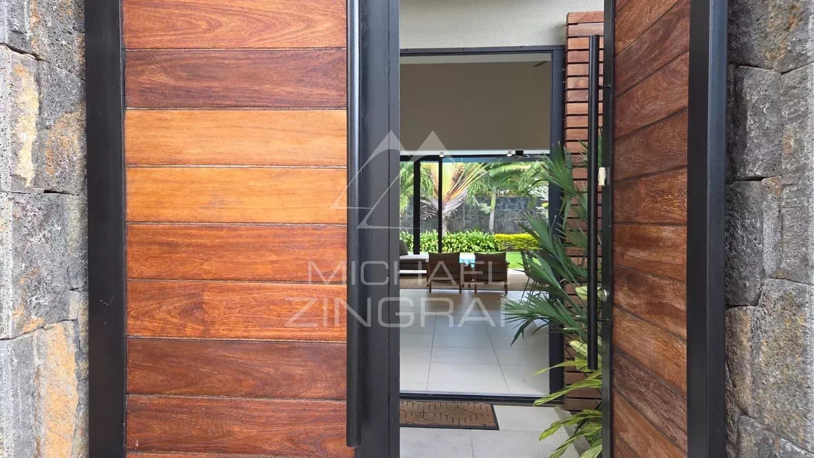 Entrance to a contemporary villa in Pereybère with wooden door and view into a bright interior space.