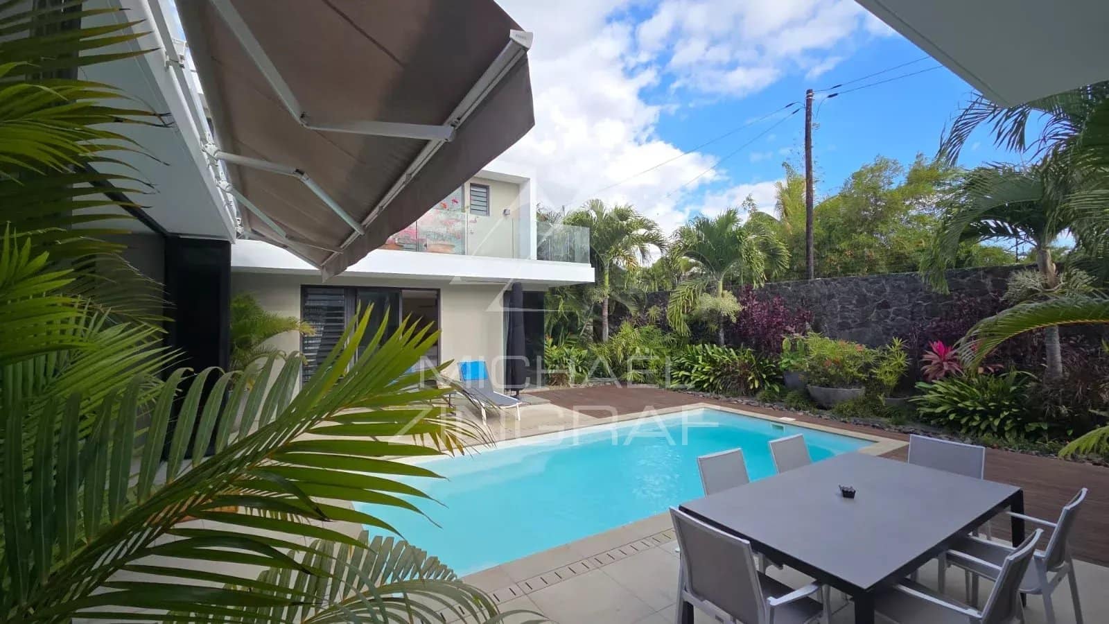 Contemporary villa with swimming pool and outdoor space in Pereybère, surrounded by greenery.