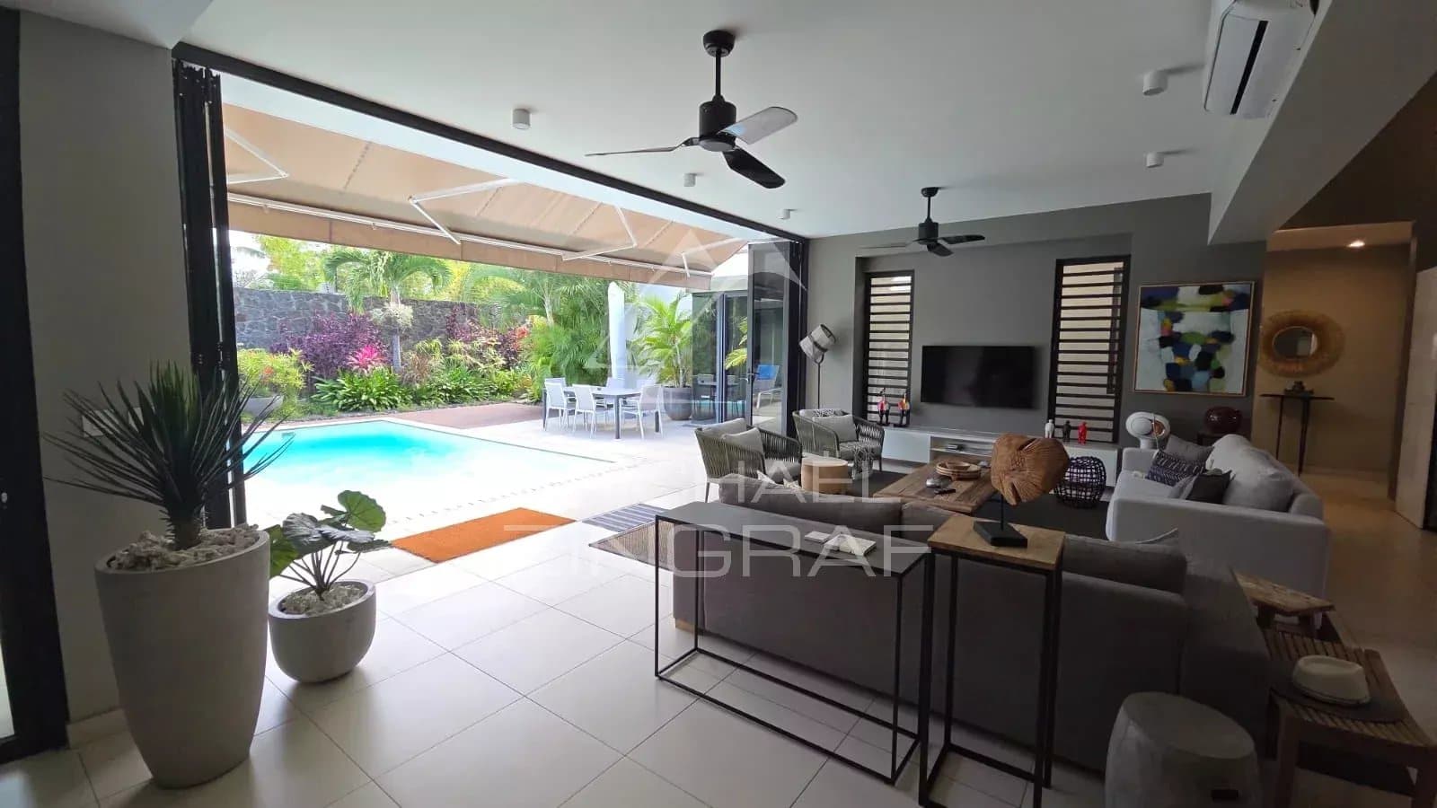 Interior of a contemporary villa in Pereybère with swimming pool and modern living room.