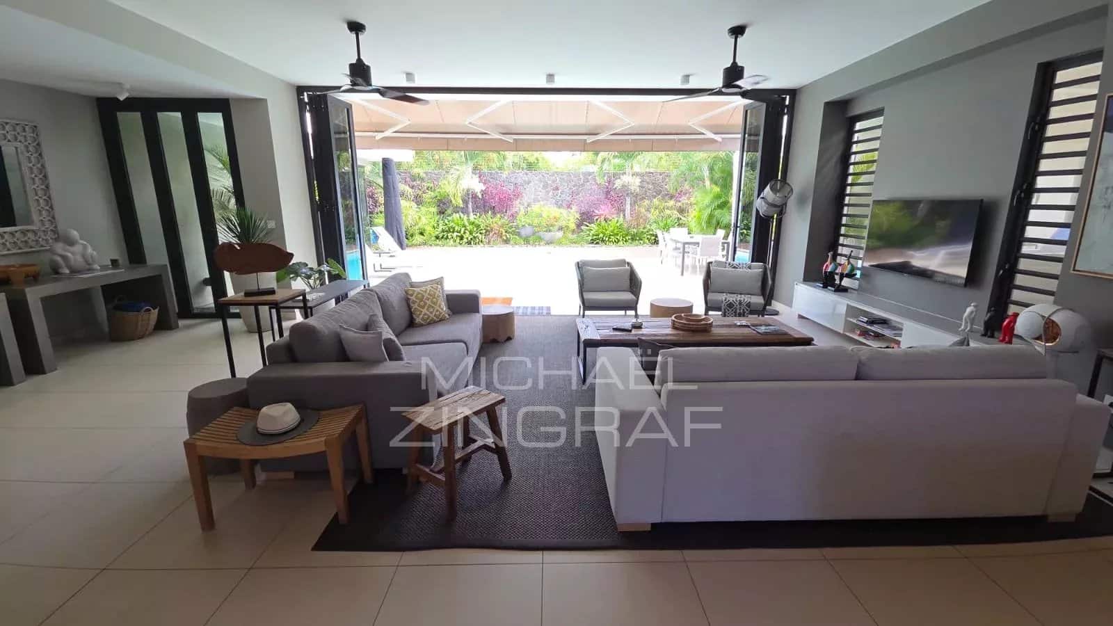 Interior of a contemporary villa in Pereybère, spacious living room with sofas and access to the outside.