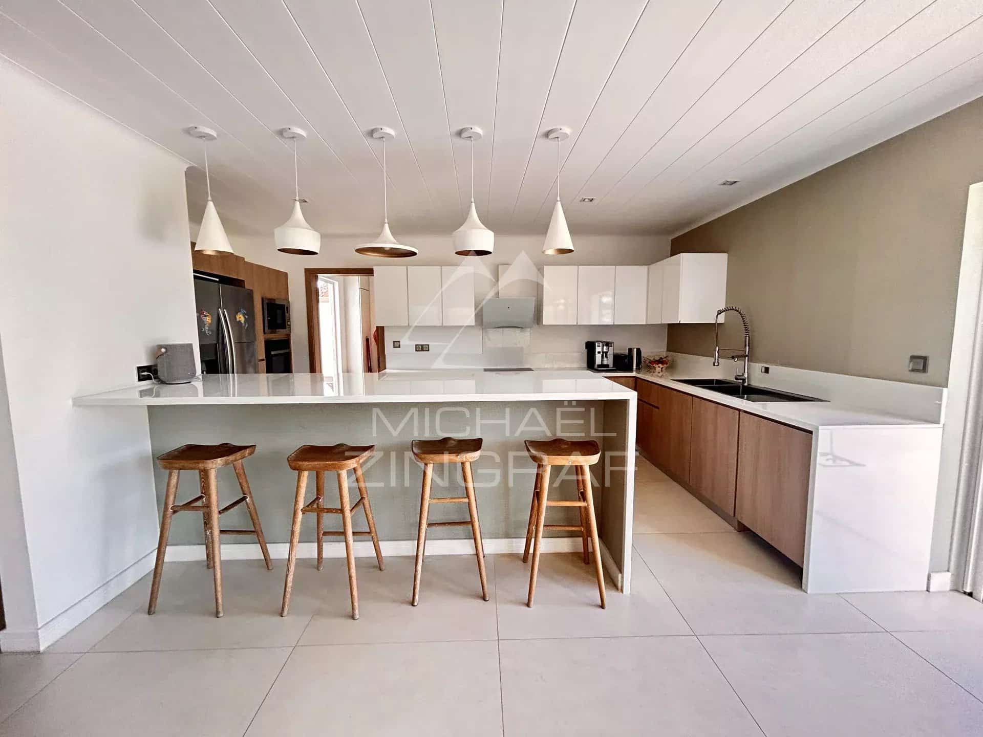 Modern and bright kitchen with bar and wooden chairs in a villa in Grand Baie.