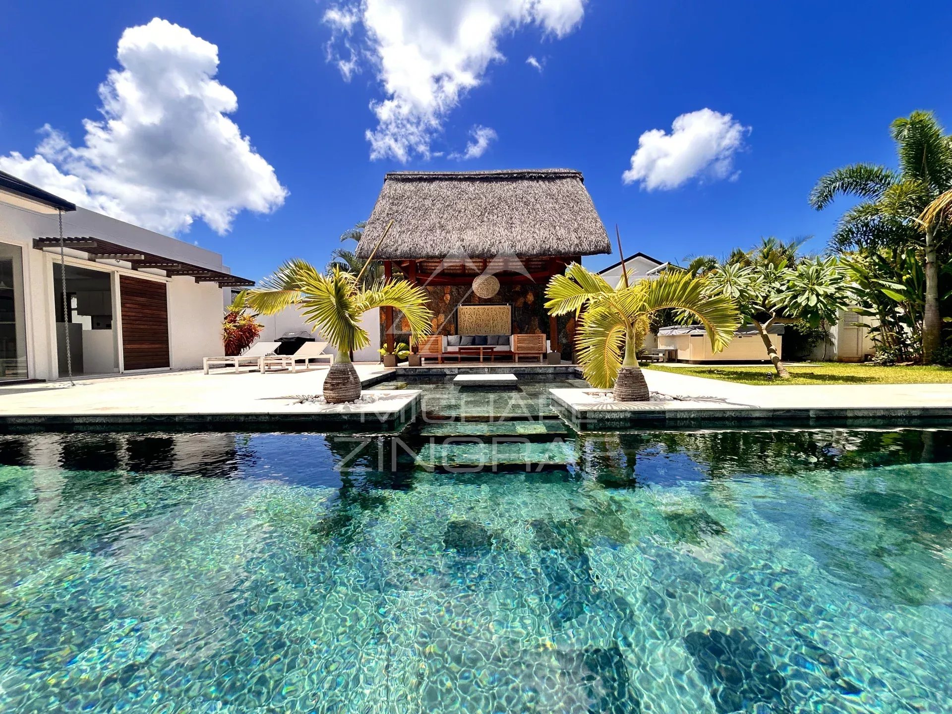 Villa with pool and garden in Grand Baie, Mauritius, under a blue sky with a few clouds.