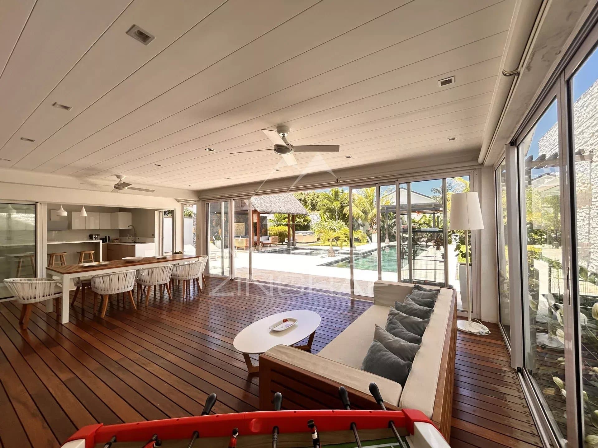 Interior of a modern villa with living room and open kitchen, overlooking the pool and garden.