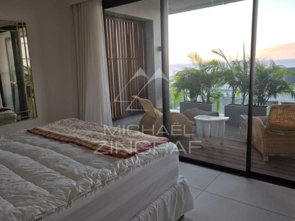 Interior of a penthouse with bed and access to a balcony, sea view.