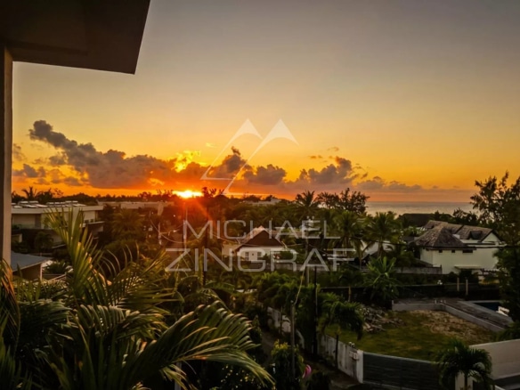 Sunset view from a penthouse in Pointe aux Canonniers, with palm trees in the foreground.