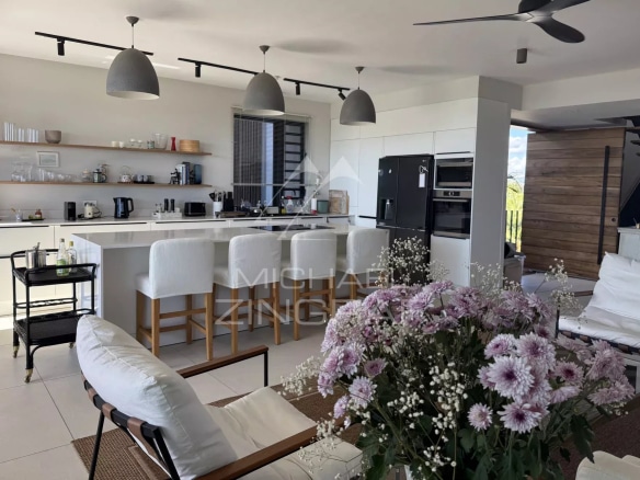 Interior of a modern penthouse with open kitchen and living room, decorated with flowers.