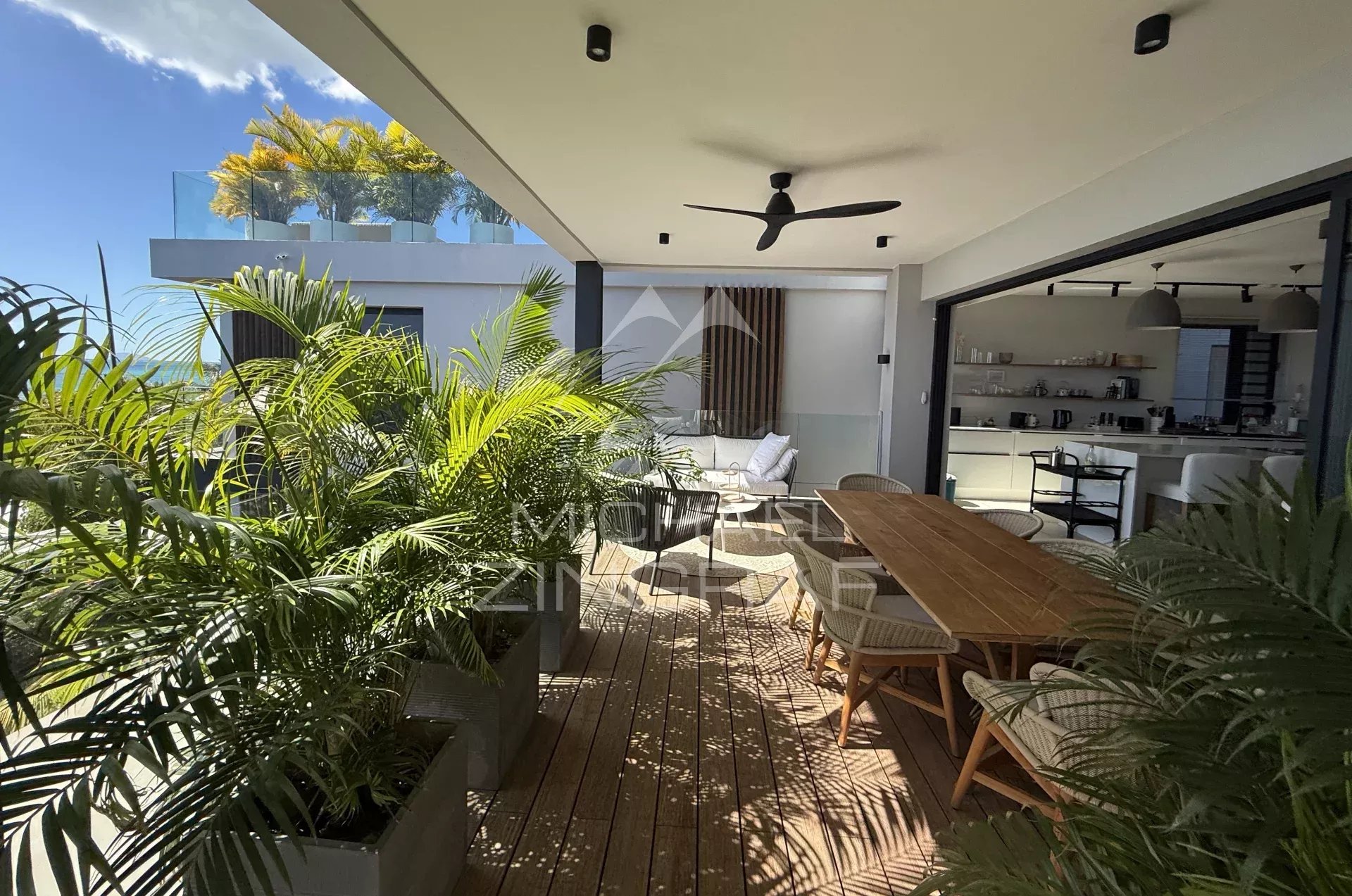Penthouse terrace at Pointe aux Canonniers Penthouse terrace with wooden furniture and plants, overlooking the modern interior.
