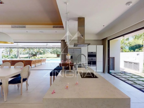 Interior of a modern villa with open kitchen and dining room, overlooking the garden.