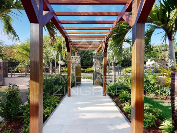 Wooden walkway leading to a modern villa surrounded by greenery in Beau Champ, Mauritius.