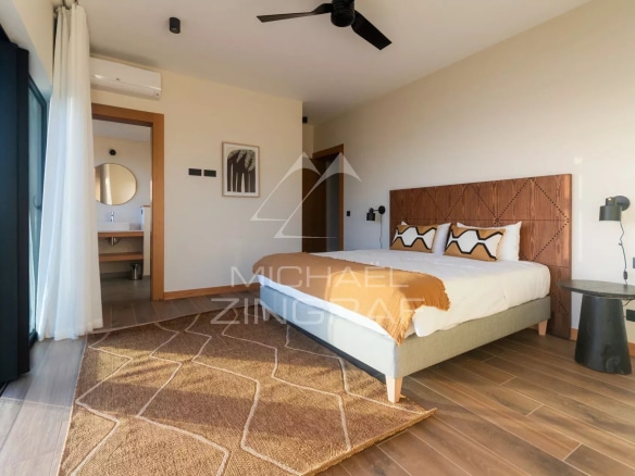 Chambre d'une villa avec lit double, décoration moderne et vue sur l'extérieur.