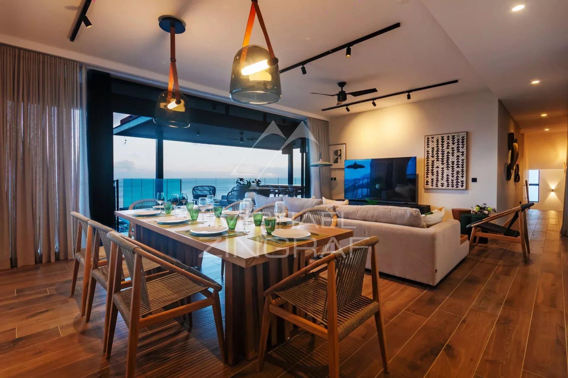 Intérieur d'une villa moderne avec salle à manger et vue sur la mer.