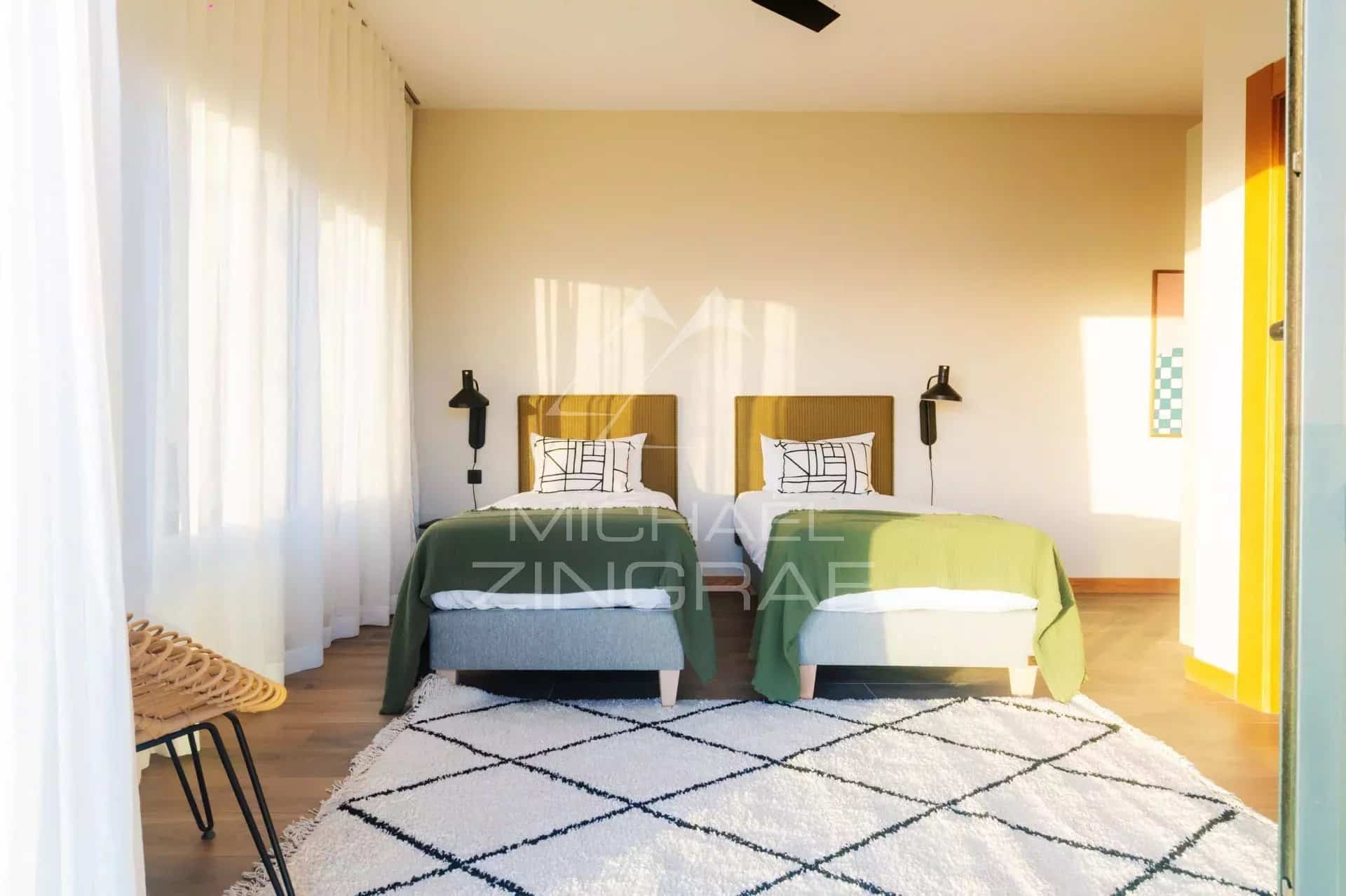 Chambre d'une villa avec deux lits simples, décoration moderne et lumineuse.