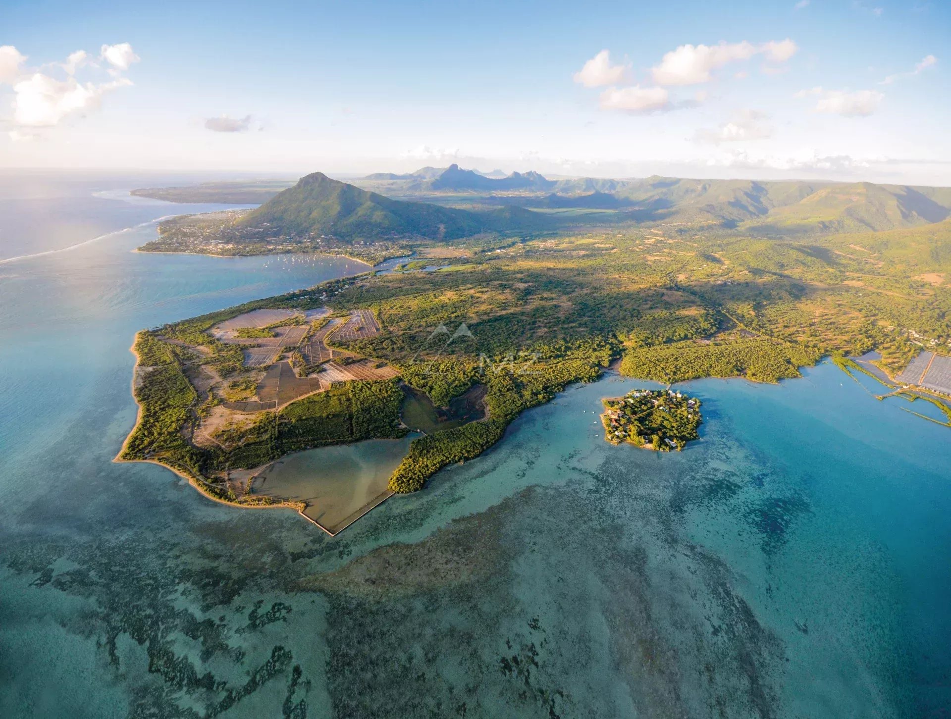 Vue aérienne de la villa N sur le golf à Rivière Noire, Île Maurice, avec montagnes en arrière-plan.