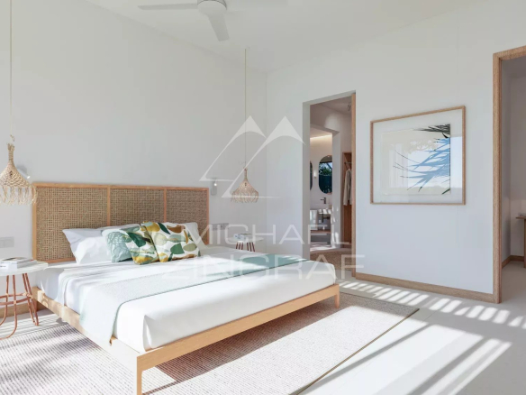 Chambre d'une villa moderne avec lit, décoration minimaliste et lumière naturelle à Rivière Noire, Île Maurice.