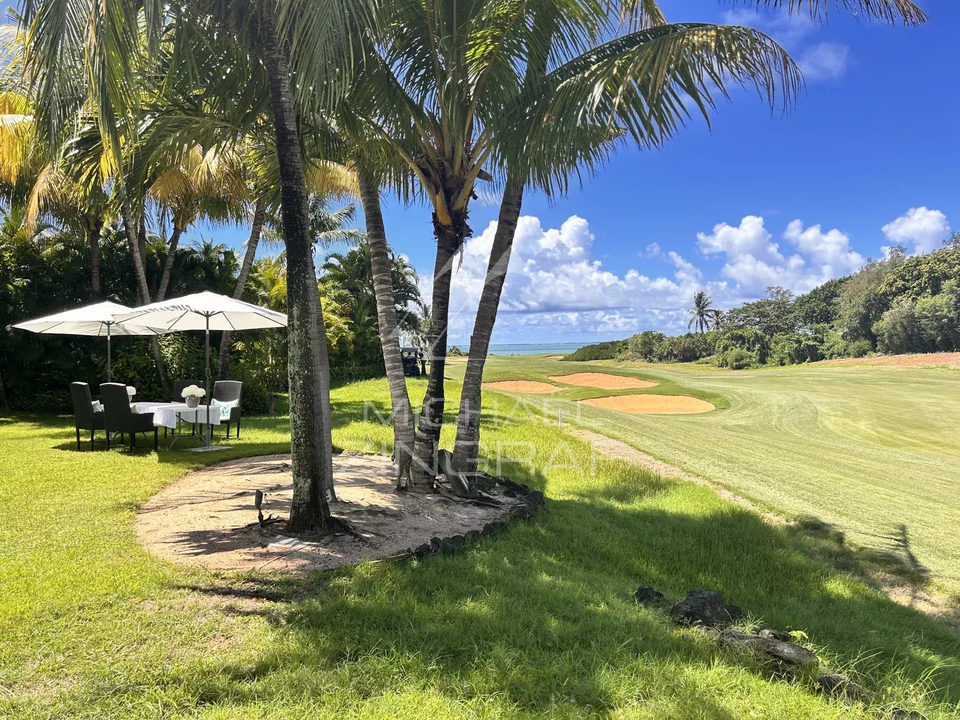 View of a villa with garden, parasol and golf course in Beau Champ.