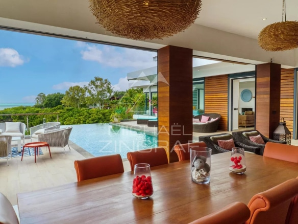 Intérieur d'une villa de luxe avec vue sur la piscine et la nature environnante.