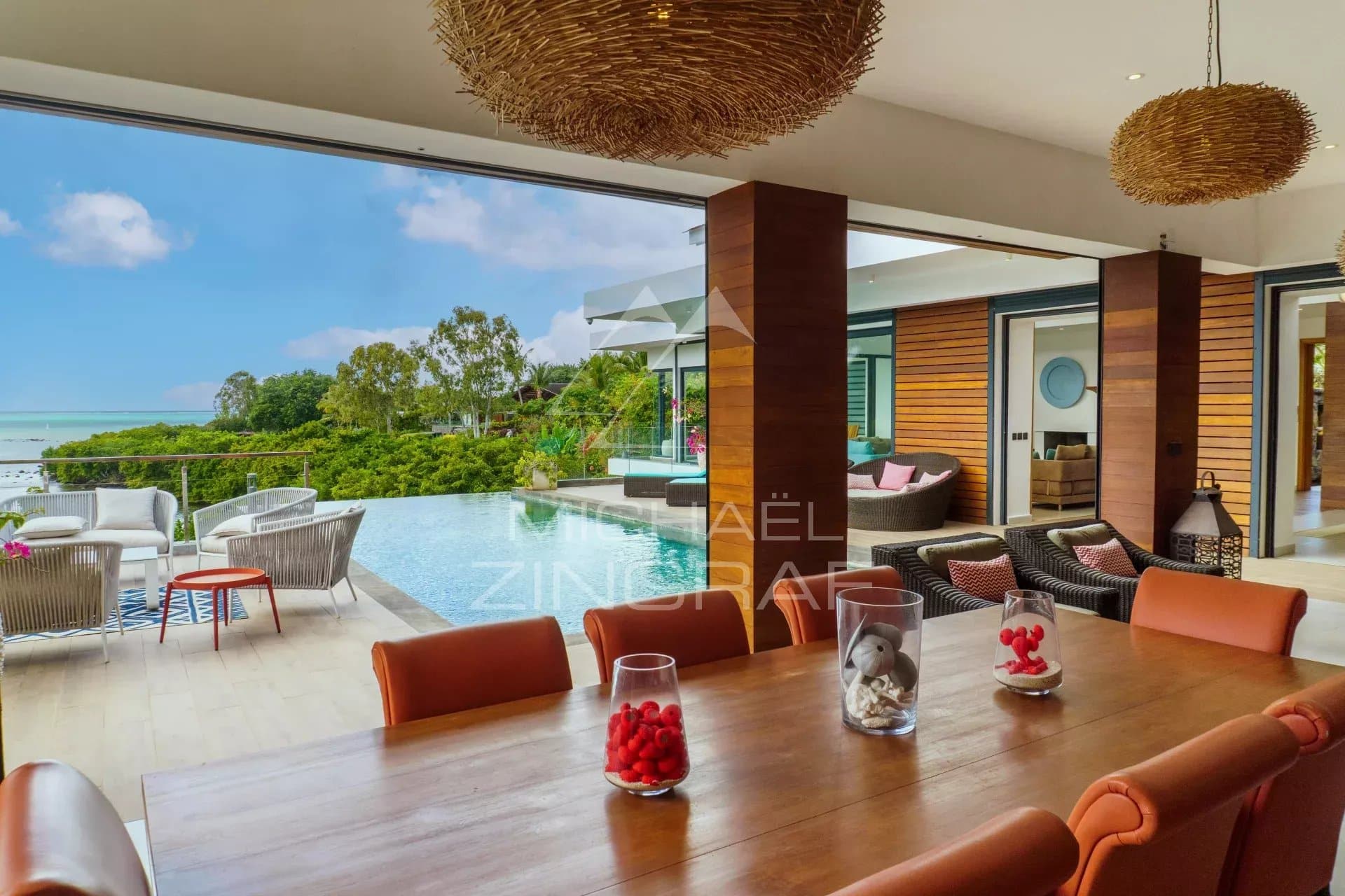 Intérieur d'une villa de luxe avec vue sur la piscine et la nature environnante.