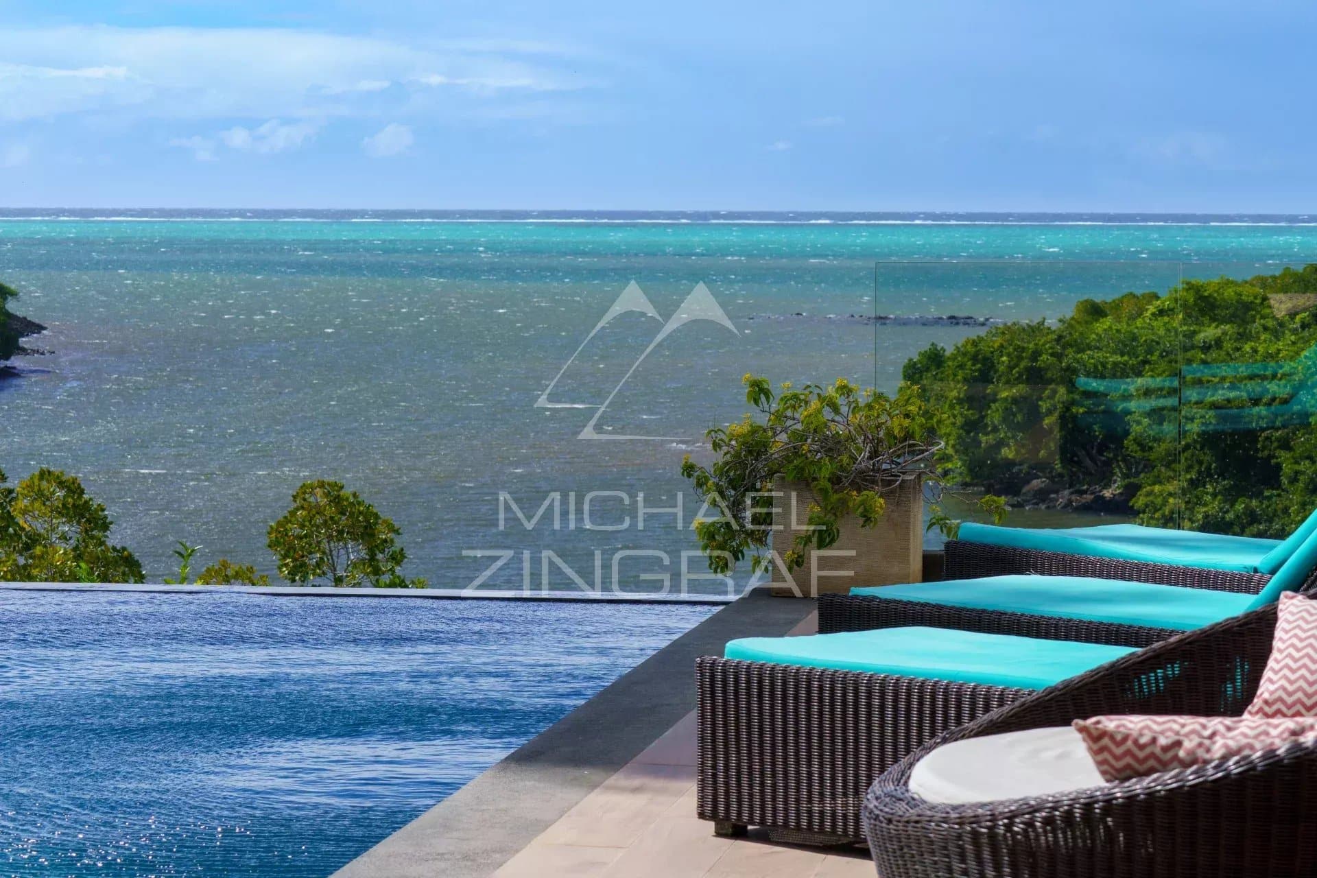 Vue sur la mer depuis une villa avec piscine à débordement et chaises longues.