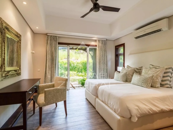 Chambre d'une villa avec lit double et accès à un jardin.