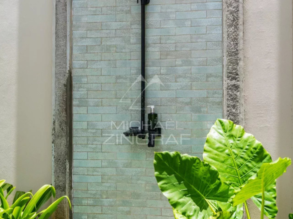 Douche extérieure moderne entourée de plantes vertes.