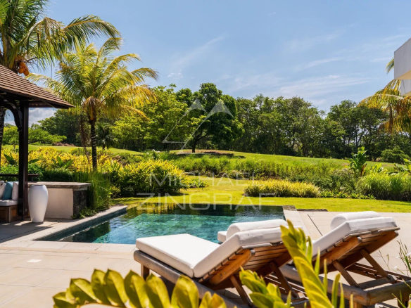 Villa contemporaine avec piscine et chaises longues face à un parcours de golf à Bel Ombre.