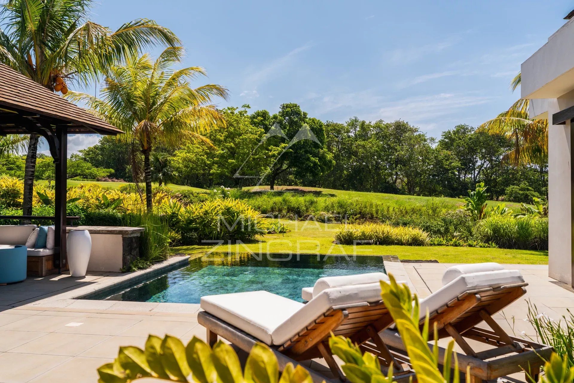 Villa contemporaine avec piscine et chaises longues face à un parcours de golf à Bel Ombre.