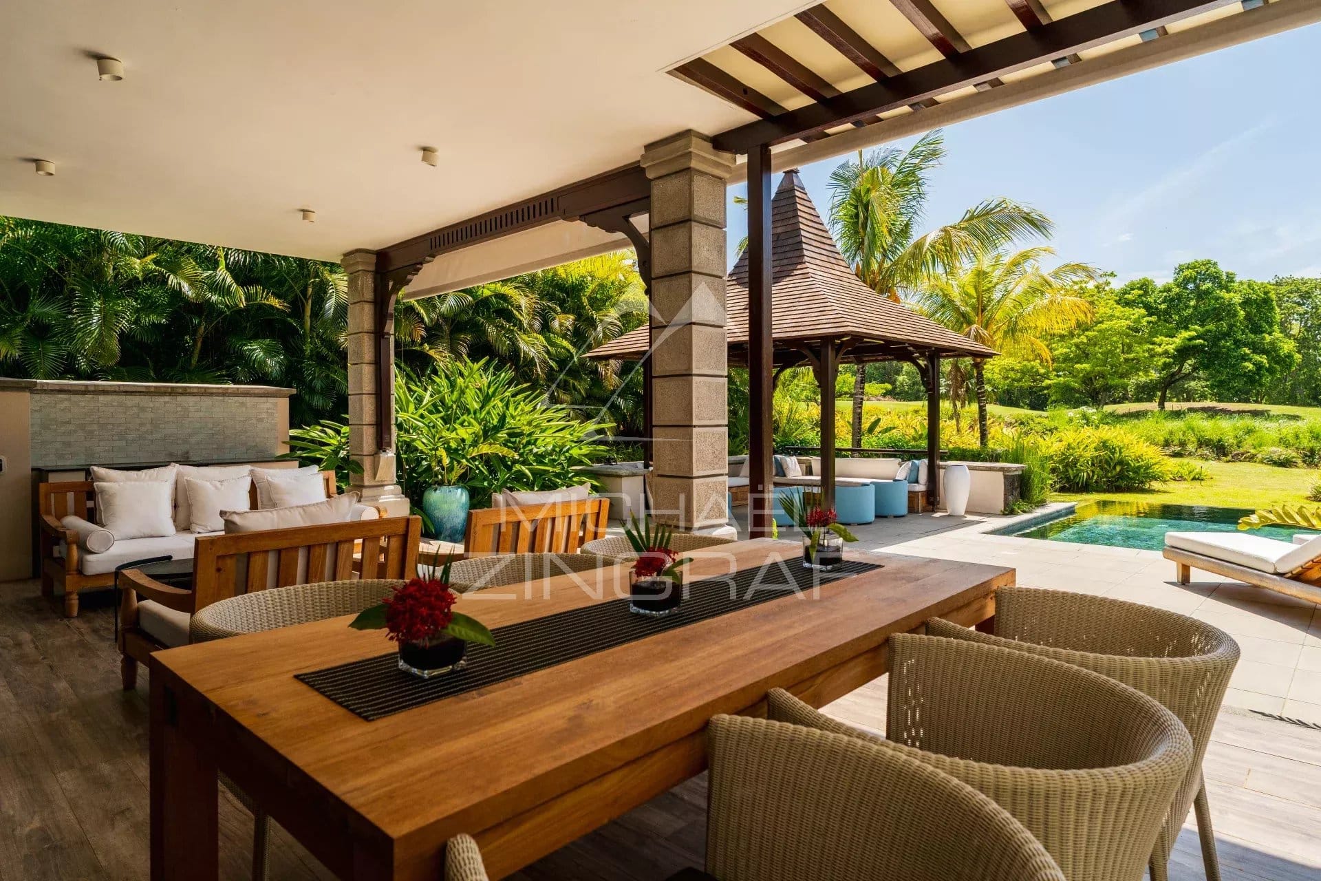 Terrasse d'une villa contemporaine avec mobilier en bois et vue sur un jardin verdoyant.