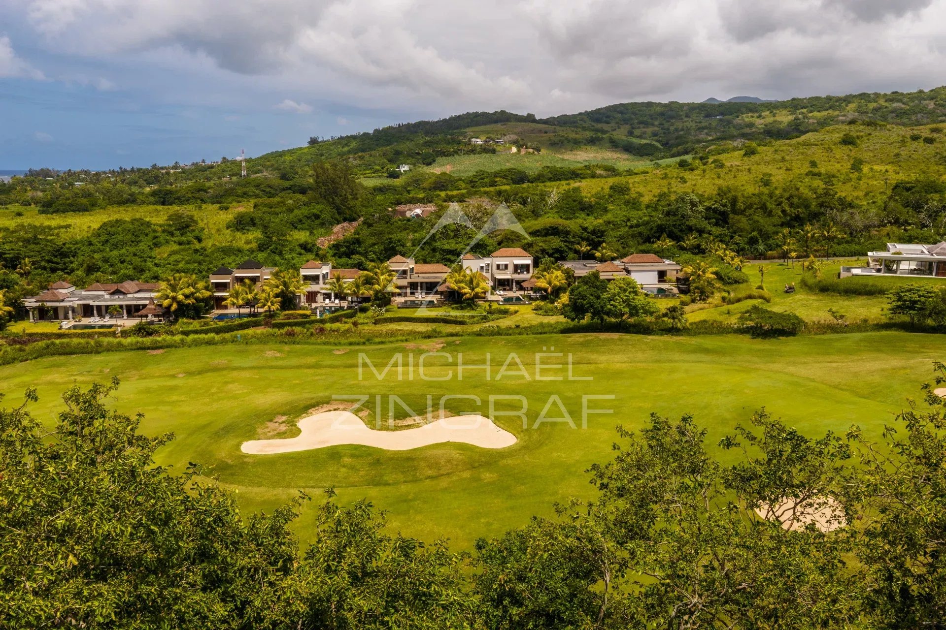 Vue aérienne d'une villa contemporaine face au golf avec un fairway et des maisons environnantes à Bel Ombre.