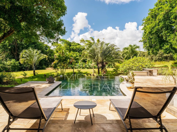 View of a villa with swimming pool and sun loungers, surrounded by greenery in Bel Ombre, Mauritius.