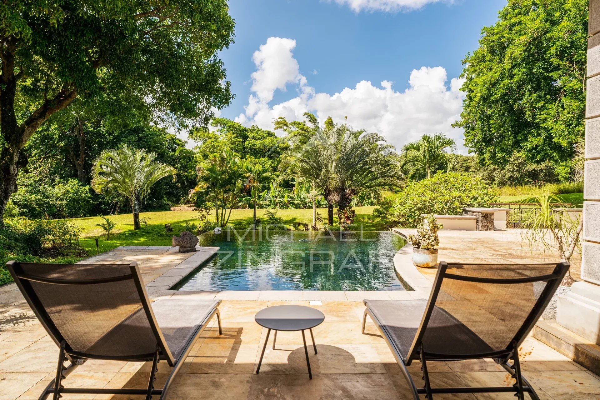 View of a villa with swimming pool and sun loungers, surrounded by greenery in Bel Ombre, Mauritius.