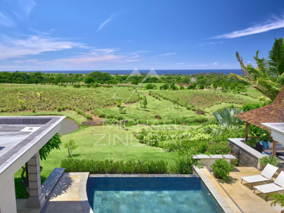 View of a villa with a swimming pool overlooking a golf course, surrounded by greenery and the ocean in Bel Ombre, Mauritius.