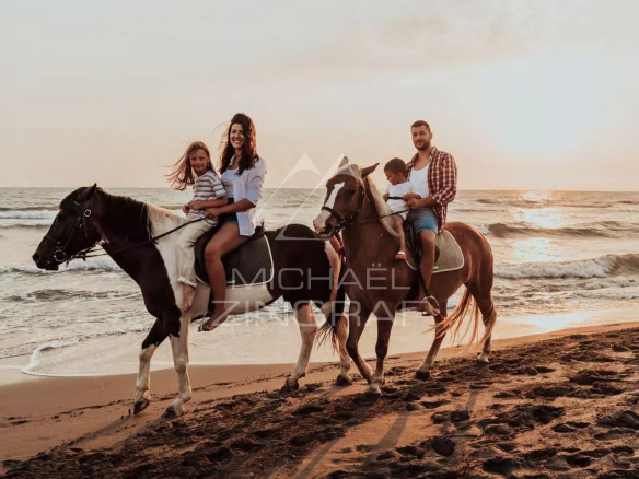 Famille à cheval sur la plage au coucher du soleil