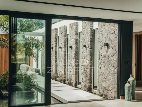Modern interior of a villa with stone walls and large bay windows.