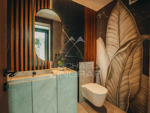 Modern bathroom with round mirror and leaf wall decor.