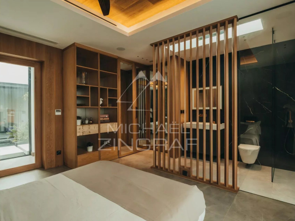 Modern bedroom with wooden divider and en-suite bathroom in a contemporary villa.