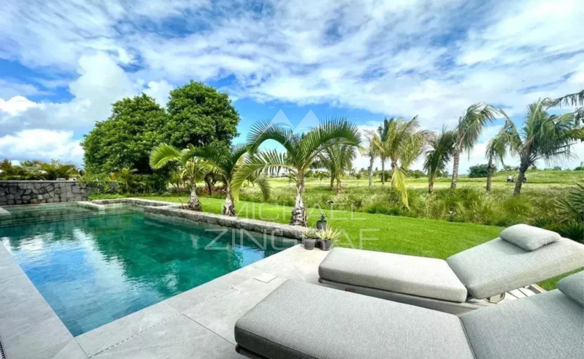 Contemporary villa with golf course views View of the pool and garden of a contemporary villa with palm trees and golf course in the background.