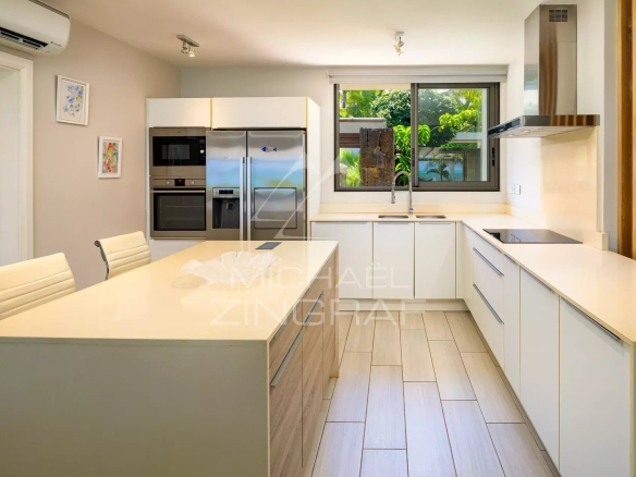 Cuisine moderne et lumineuse d'une villa à Haute Rive, avec îlot central et équipements intégrés.
