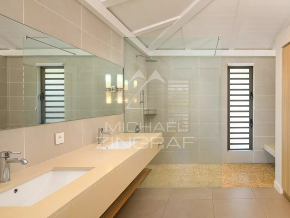 Salle de bain moderne avec douche et lavabo dans une villa à Haute Rive.