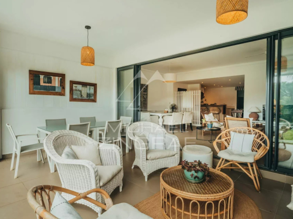 Bright living room of a 3-bedroom apartment with rattan furniture and garden view.