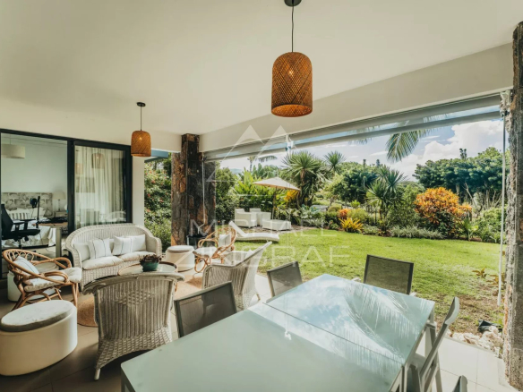 Apartment terrace with wicker furniture and view of a landscaped garden in Haute Rive.