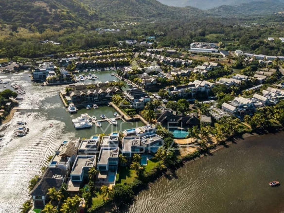 Vue aérienne d'une villa de luxe avec piscine et bateaux à Rivière Noire, entourée de montagnes et de nature.