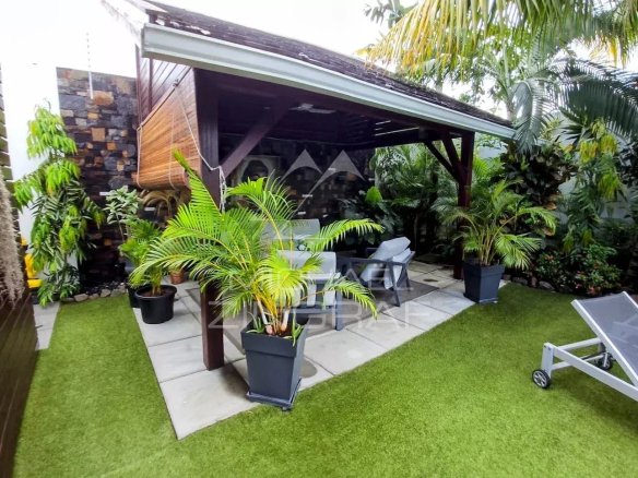 Outdoor space of a villa in Pereybère with plants and a seating area.