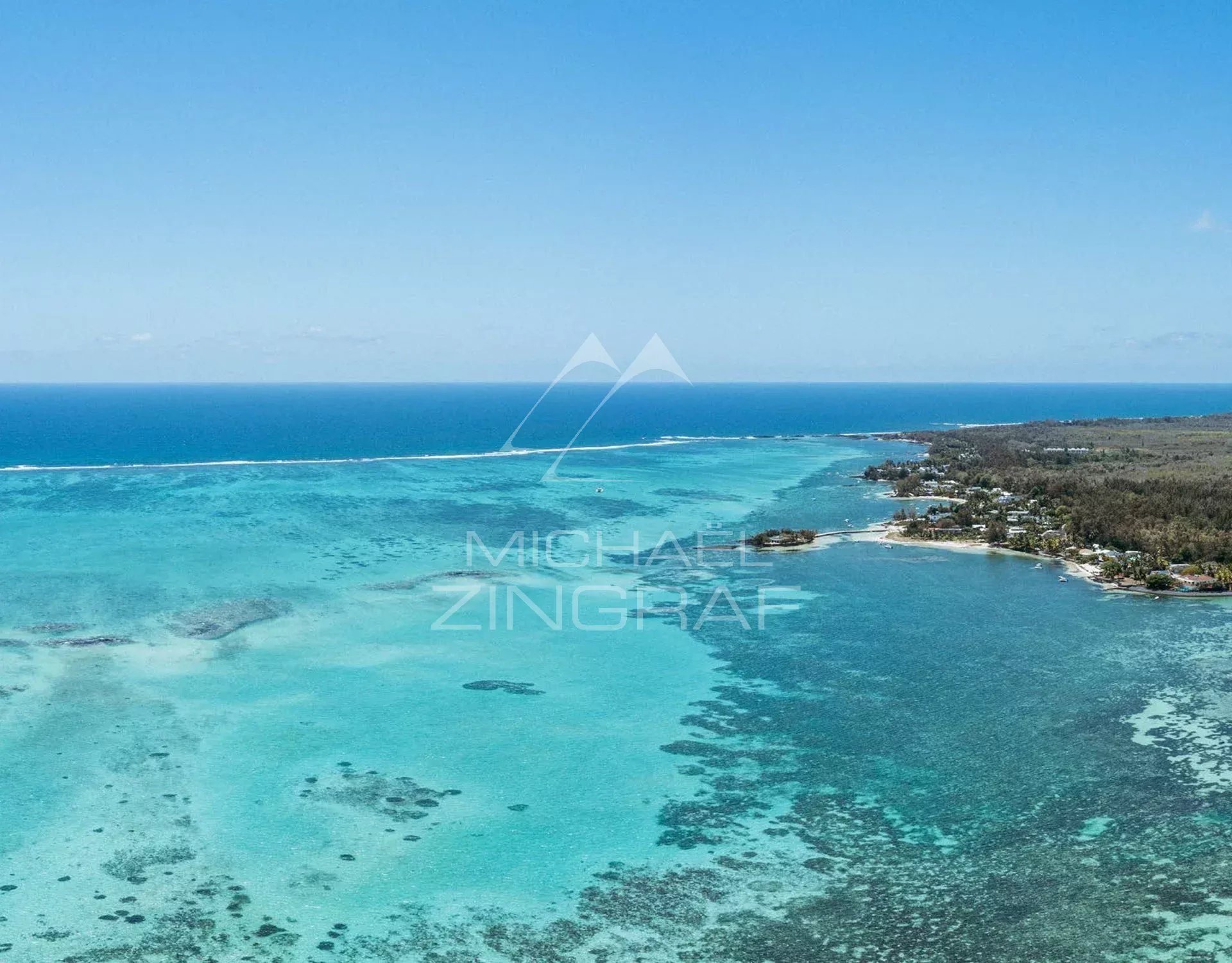 Aerial view of Roches Noires with turquoise sea and coastline.