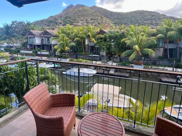 Vue depuis un balcon sur la marina avec des bateaux et des montagnes en arrière-plan.
