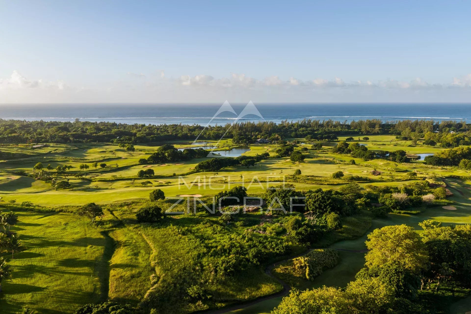 Vue aérienne des villas de luxe à Heritage Villas Valriche, Bel Ombre, avec un paysage verdoyant et l'océan en arrière-plan.