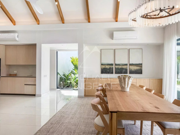Intérieur d'une villa moderne avec salle à manger et accès à un jardin.