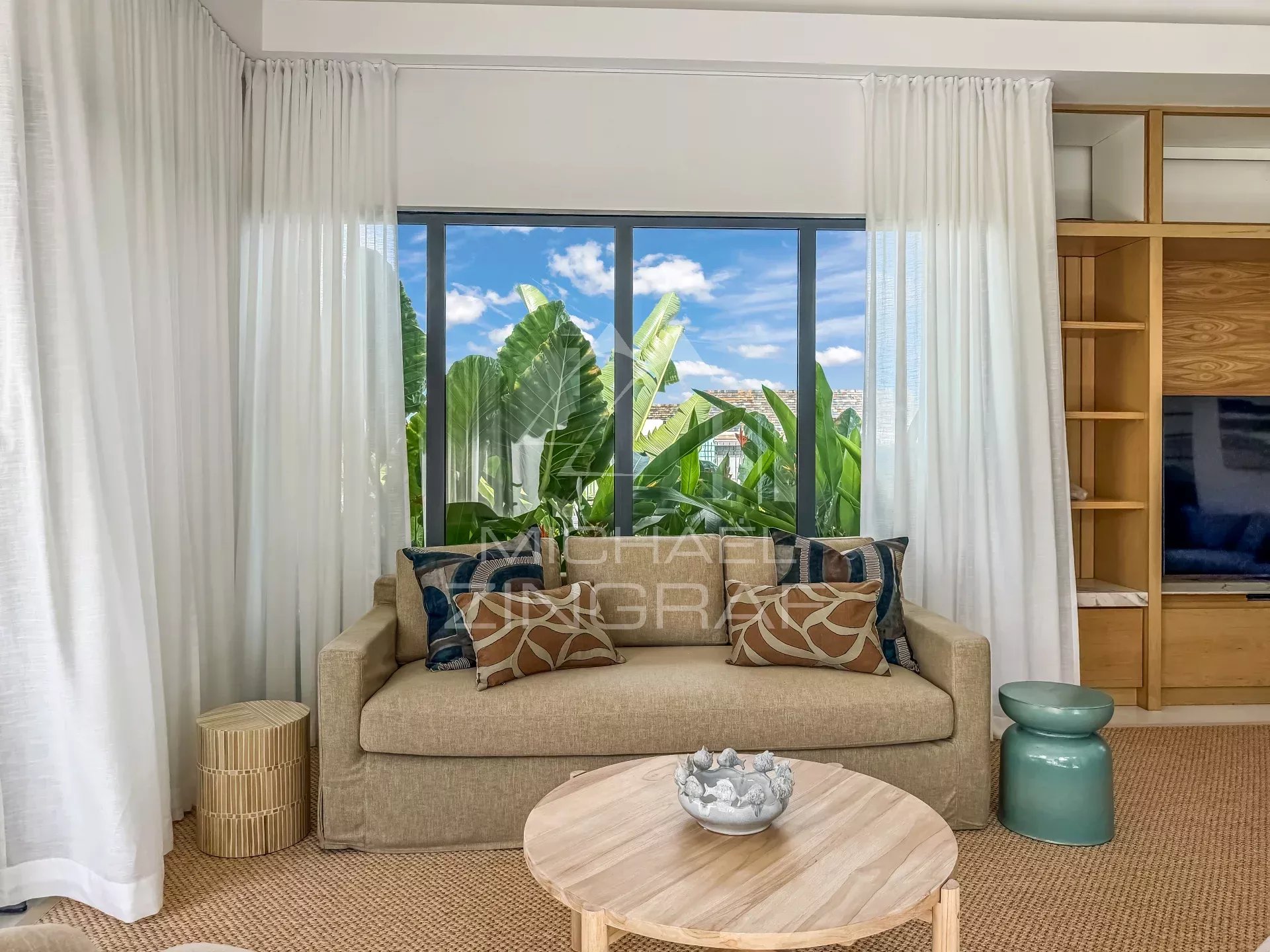 Intérieur d’une villa à Mont Choisy Golf Estate Intérieur d'une villa avec canapé et vue sur des plantes tropicales