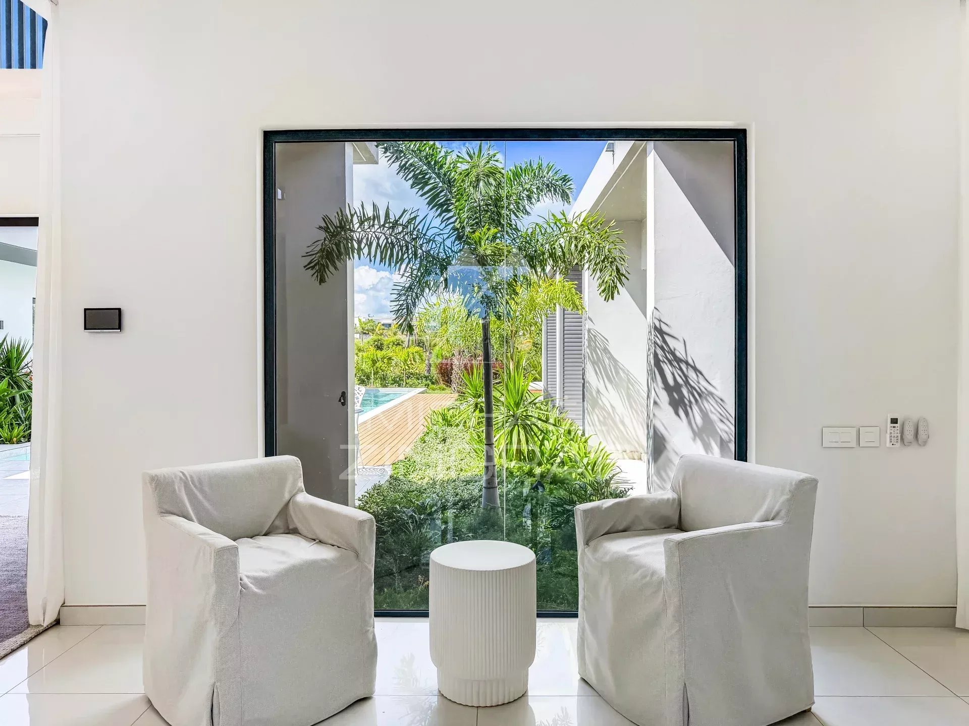 Intérieur de la villa au Mont Choisy Golf Estate Intérieur d'une villa avec deux fauteuils et vue sur un jardin verdoyant.