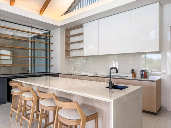 Cuisine moderne avec un îlot central et des tabourets en bois dans une villa de luxe.