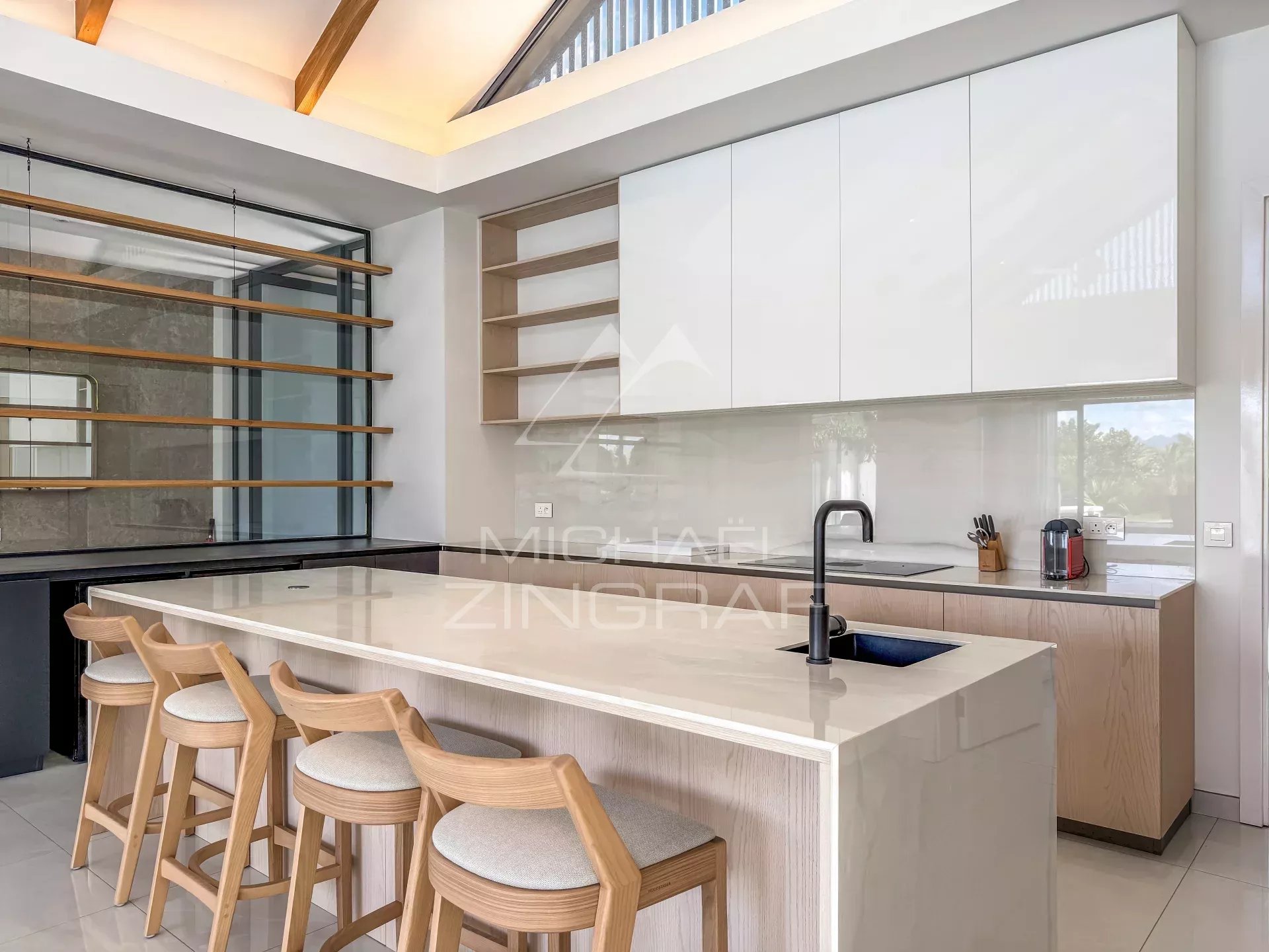 Cuisine d’une villa de luxe à Mont Choisy Golf Estate Cuisine moderne avec un îlot central et des tabourets en bois dans une villa de luxe.